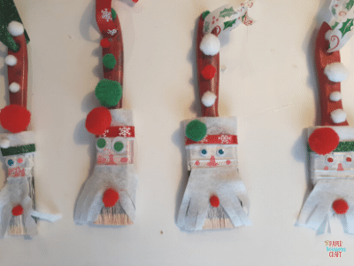 Four different DIY Santa paintbrush ornaments.