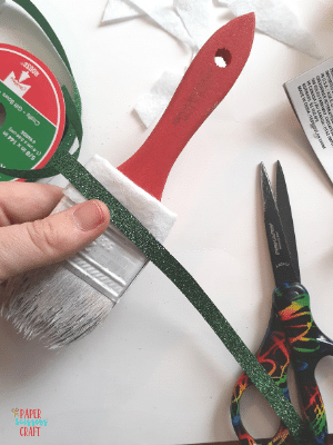 Green ribbon being attached to white felt on the Santa paintbrush ornament.