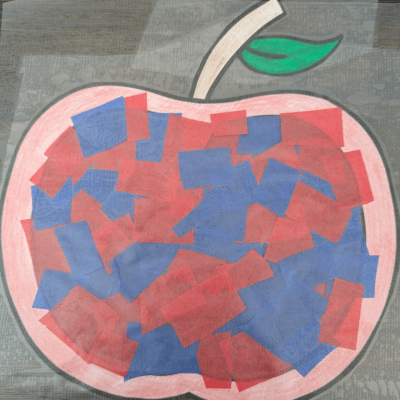 Apple suncatcher craft in between two pieces of contact paper.