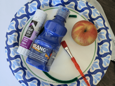 Supplies needed for apple stamping on a paper plate.