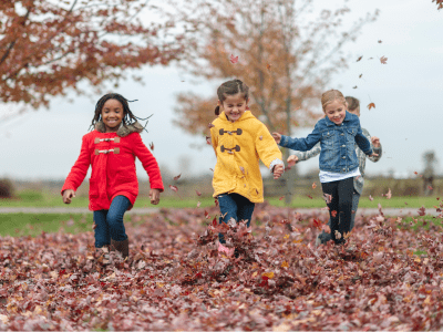 Kids running through a pile of leaves.