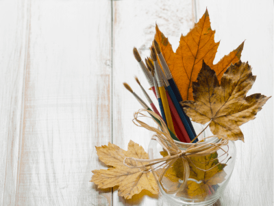 Vase with fall colored leaves and paintbrushes.