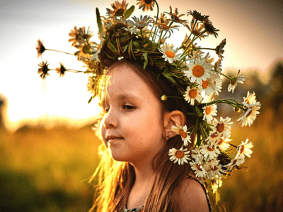 Little girl wearing a crown created with daisies and dandelions.