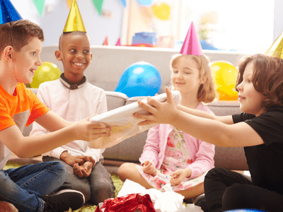 Kids with party hats and sitting in circle opening presents.