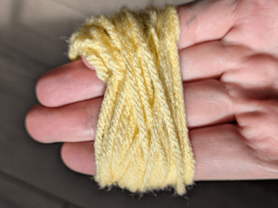 Yellow yarn wrapped many times around four fingers.