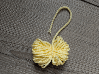 Yellow yarn tied together to form a pom-pom.